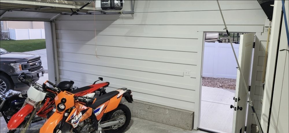 Garage floor cluttered with dirt bikes before Goat Garages installed wall storage